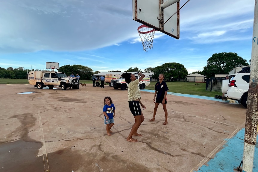 Kids play on a rural concrete basketball court