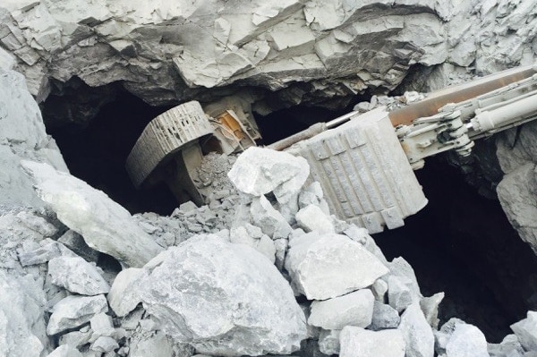 An excavator stuck upside down in hole from old underground mine workings
