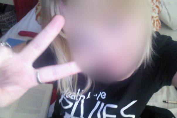 A blurred photo of a woman giving a 'peace sign' with her fingers.