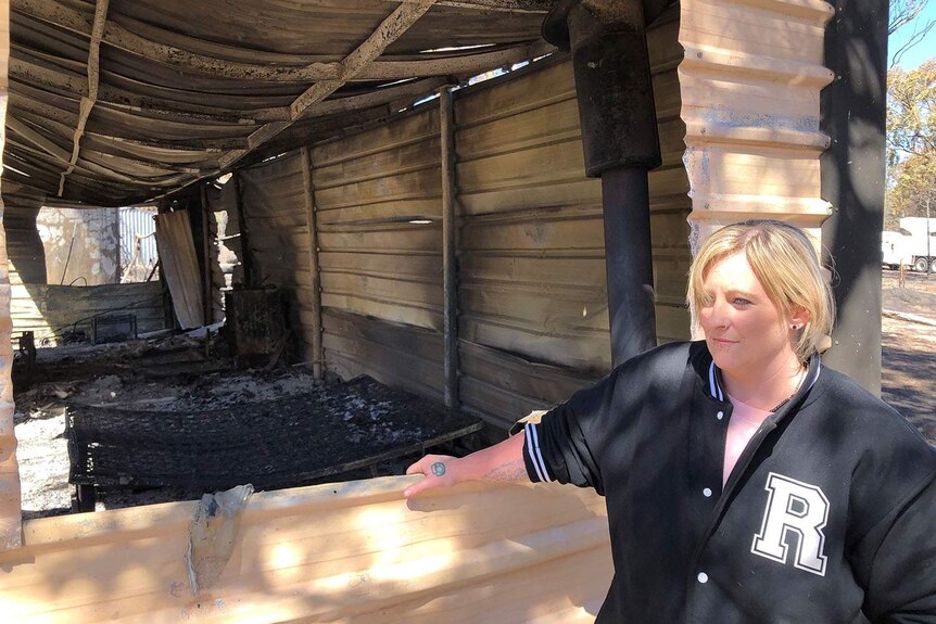Nykki Sutherland stands against her bushfire-destroyed property at Stanthorpe.