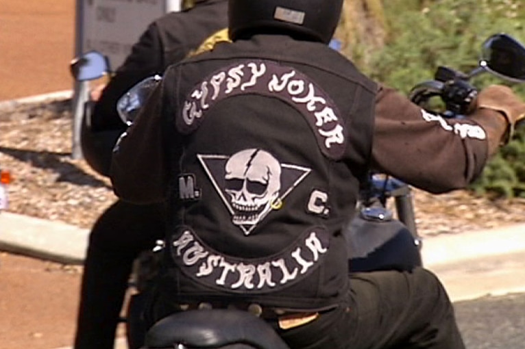A Gypsy Jokers bikie gang member rides his bike away from the camera.