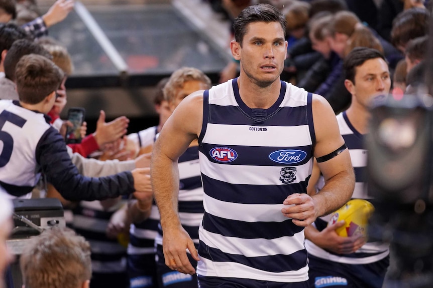 An AFL player runs out onto the ground for a semi-final match showing no emotion.