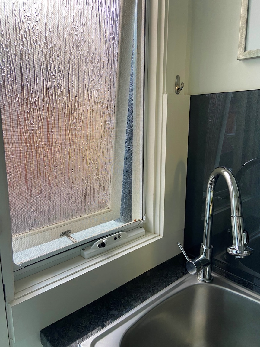 A photo of a partially open window next to a sink