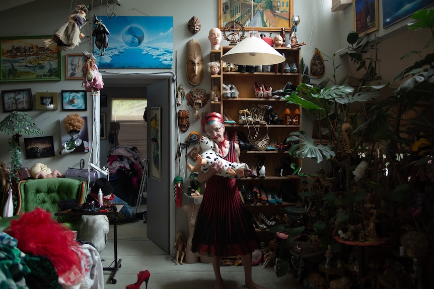 Art photograph of a woman surrounded by numerous curios in her own home