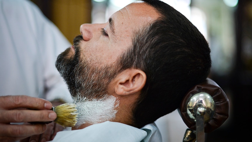 A man gets his beard trimmed at a barber shop