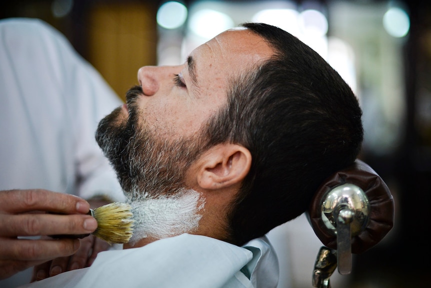 A man gets his beard trimmed at a barber shop