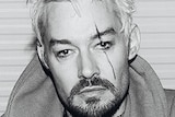 A black and white photograph of Daniel Johns sitting on the ground.