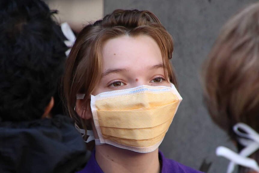 A young person wearing a yellow surgical mask.