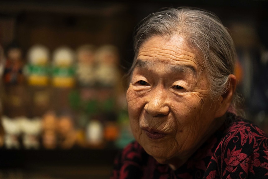 An older Japanese woman looking thoughtful in her home
