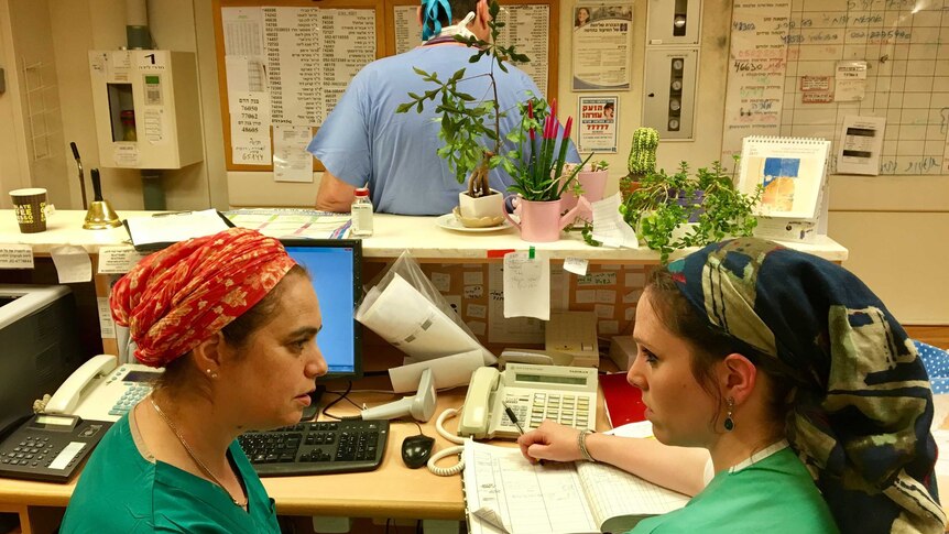 Midwife Daphna Strassberg sits behind a desk and consults with a colleague in Jerusalem hospital.