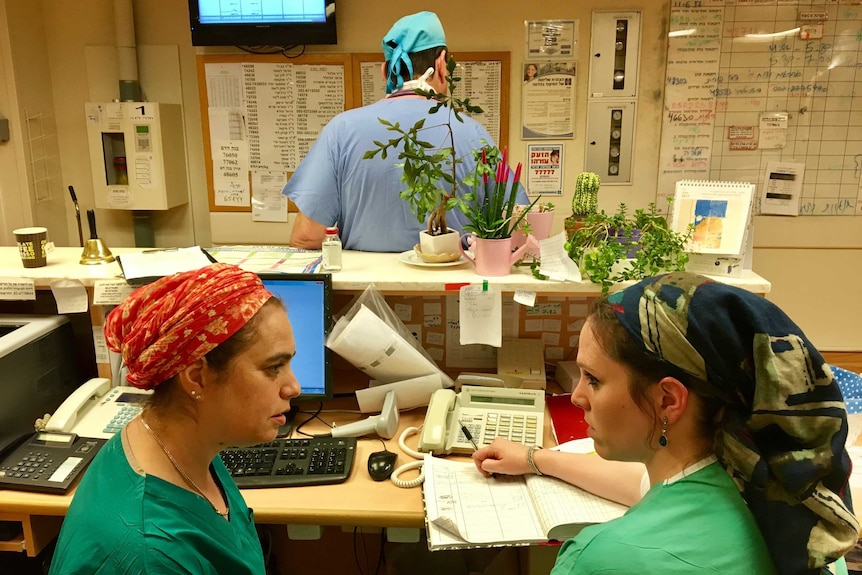 Midwife Daphna Strassberg sits behind a desk and consults with a colleague in Jerusalem hospital.