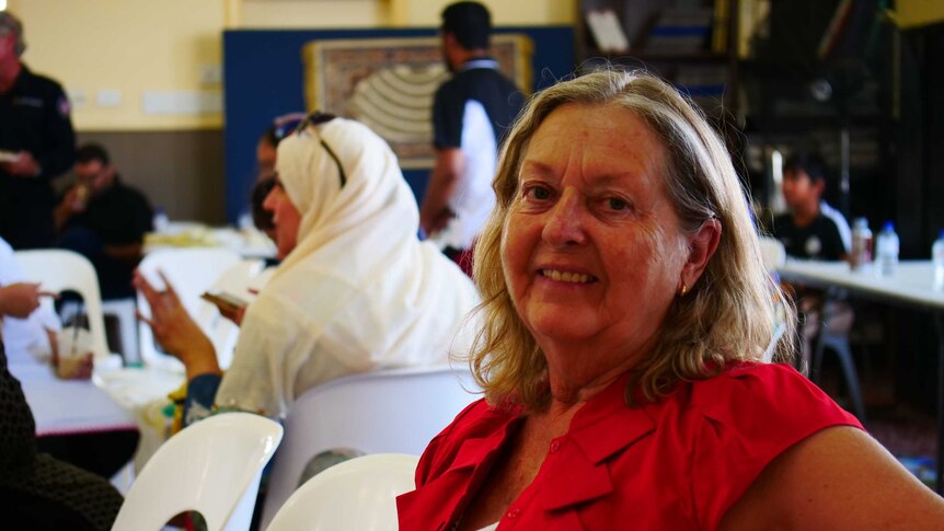 Woman with blonde hair sitting in a mosque smiling at the camera