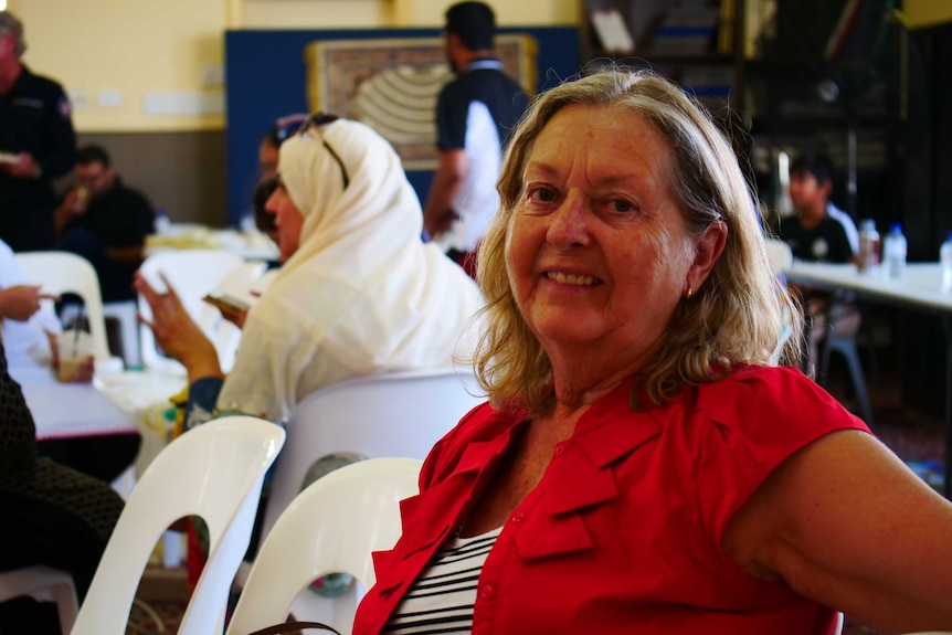 Woman with blonde hair sitting in a mosque smiling at the camera