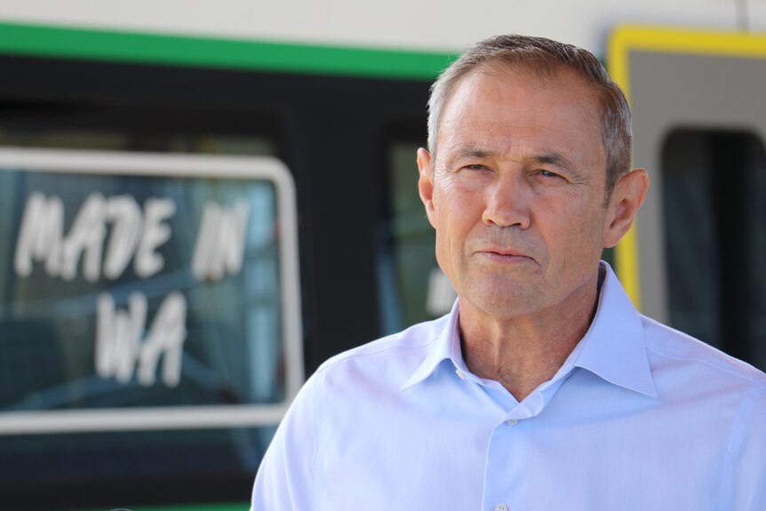 WA Premier Roger Cook stands outside in front of a train with "made in WA" in the background.
