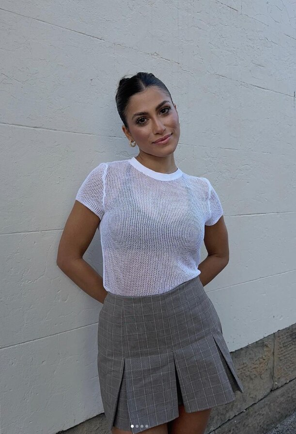A girl standing with a white tshirt and skirt on 