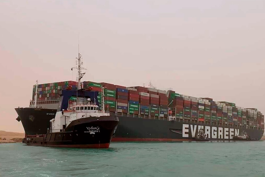 Un bateau navigue devant un énorme cargo, nommé Ever Green,