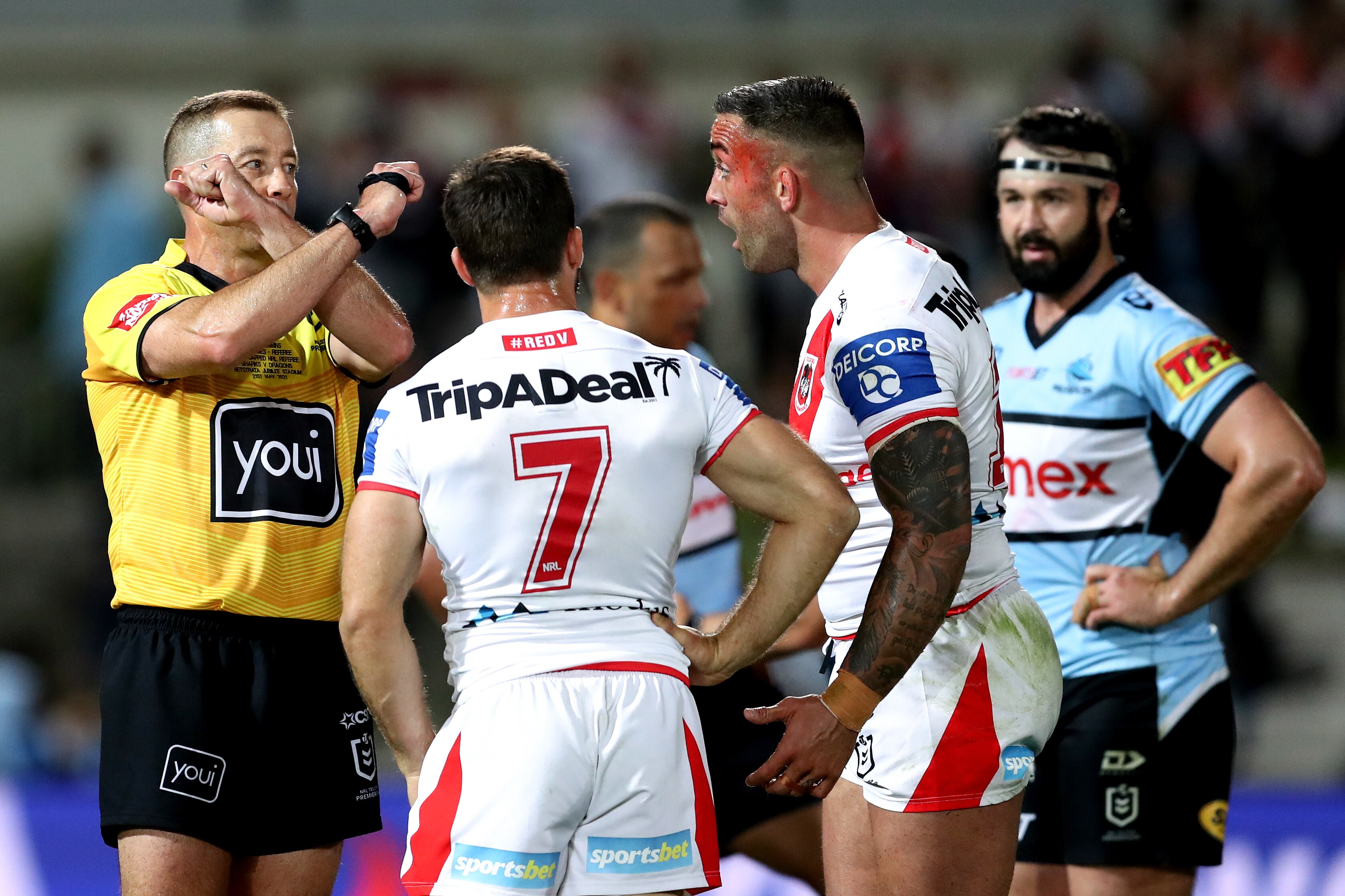 Ben Cummins crosses his arms in front of his face as two St George players look on