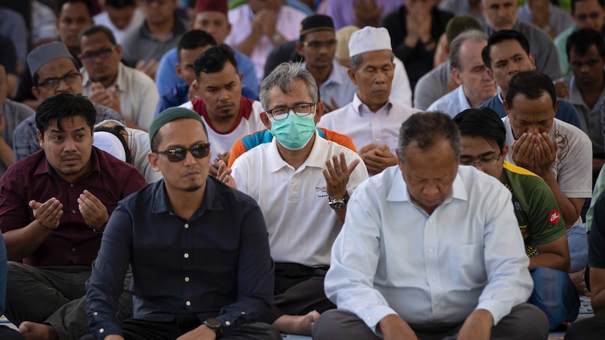 A group of worshippers sit on the floor of the mosque with heads bowed in Kuala Lumpur.