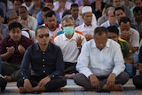 A group of worshippers sit on the floor of the mosque with heads bowed in Kuala Lumpur.