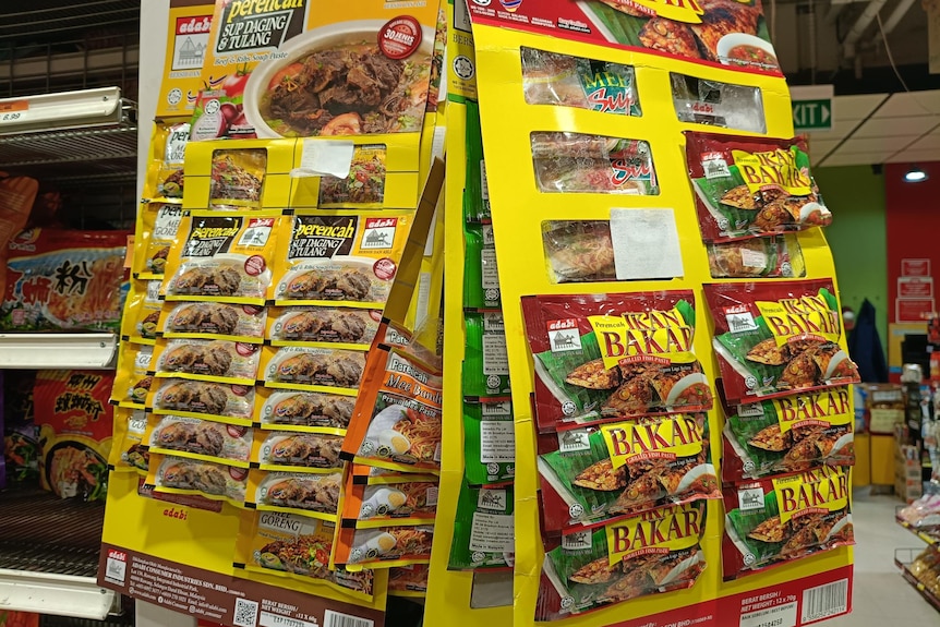 A number of products in small plastic packages sold individually hang on supermarket shelves.