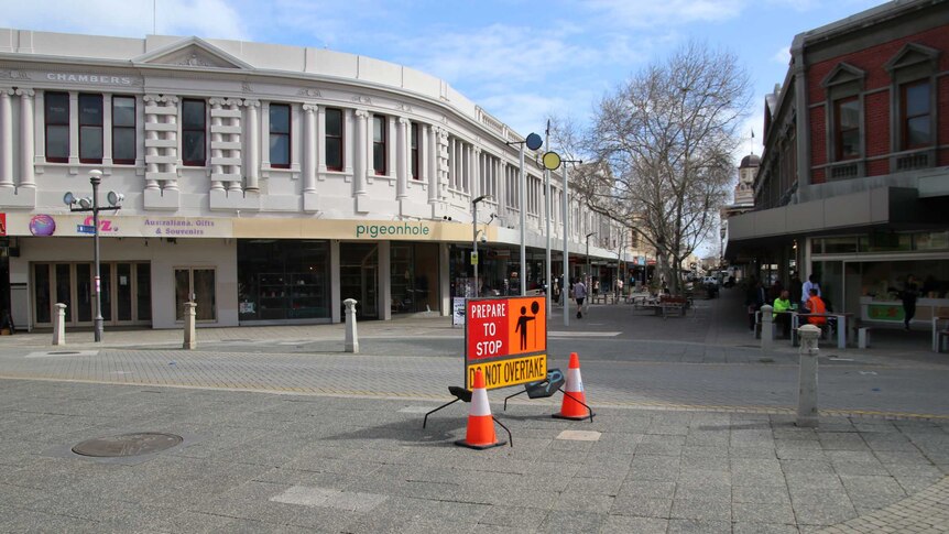 View of a quiet shopping mall in Fremantle with a 'prepare to stop' sign in the foreground.