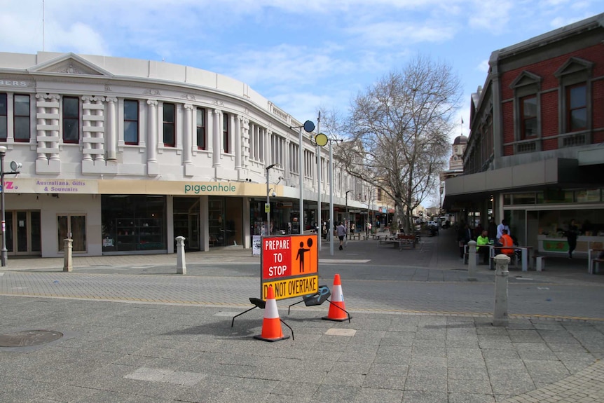 View of a quiet shopping mall in Fremantle with a 'prepare to stop' sign in the foreground.