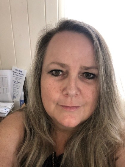 A middle aged woman smiling at the camera 