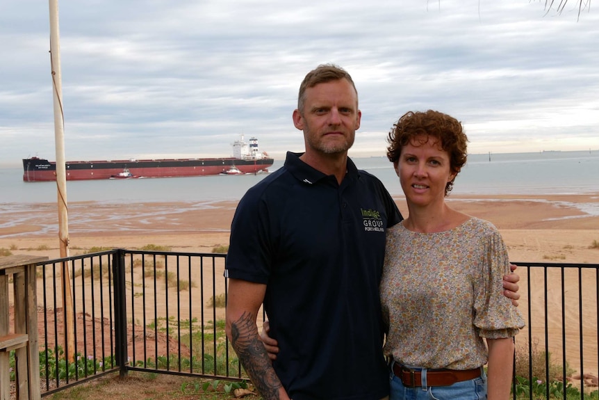 Glenn and Lisa Robertson standing on the verandah of their Port Hedland home, with a bulk carrier vessel in the background