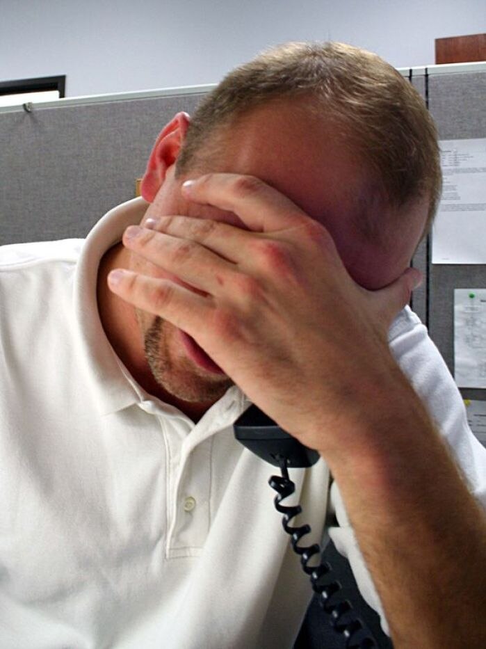 A man in an office holds his head in a distressed fashion