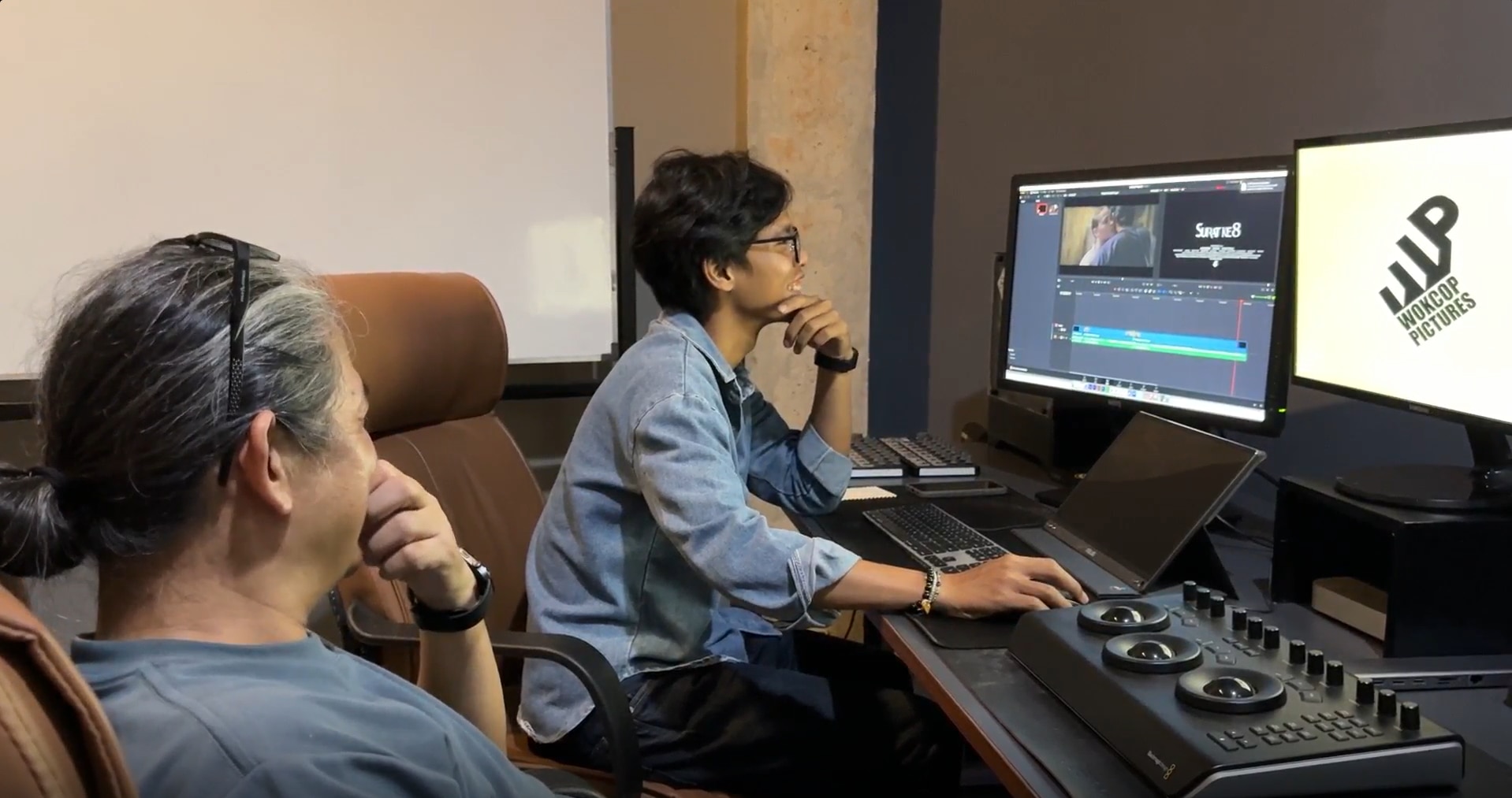 Two men sitting down in front of computer screens.