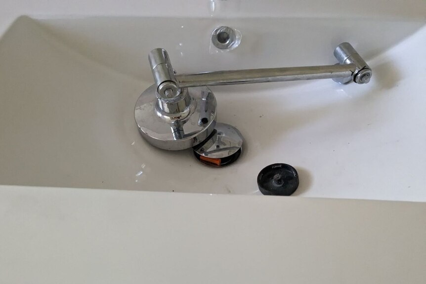 A broken-off tap laying in a sink.