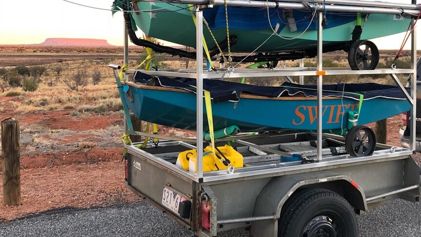 Small minnow sailing boats on back of trailer in the desert.