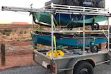 Small minnow sailing boats on back of trailer in the desert.