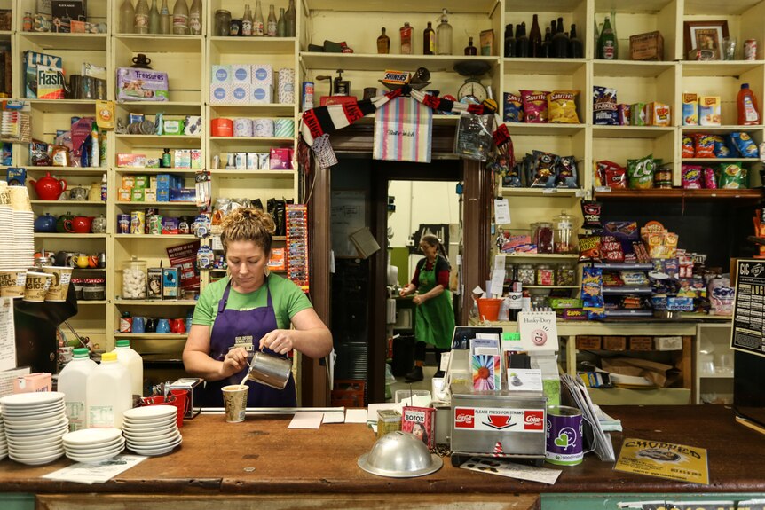 A woman makes a coffee in a well-stocked country store