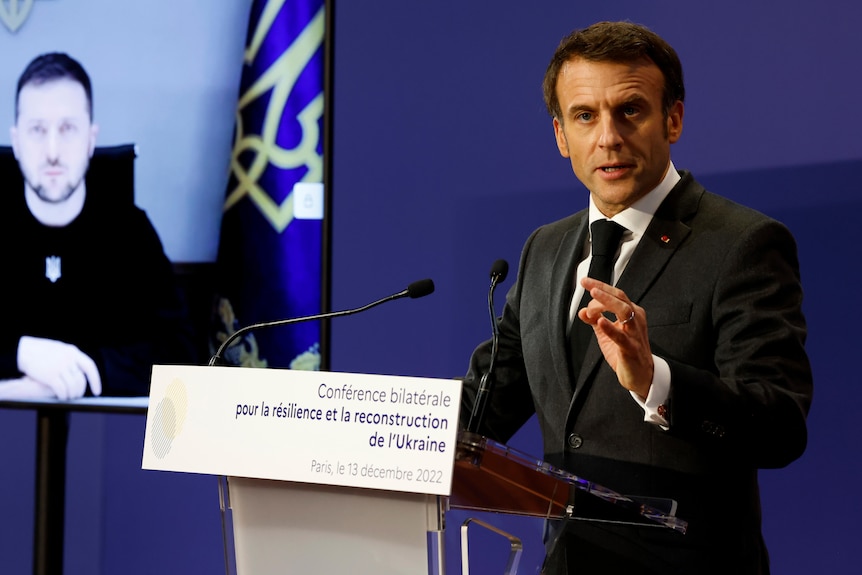 Macron annuisce sul podio con Zelenskyy sullo schermo del collegamento video sullo sfondo