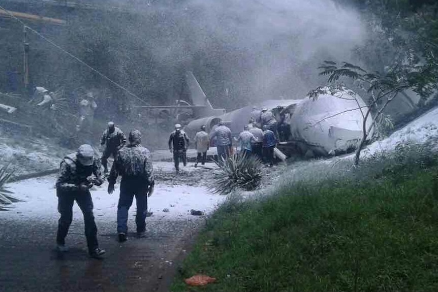 Police and citizens help rescue survivors of the Honduras plane crash as the private jet is doused in foam.