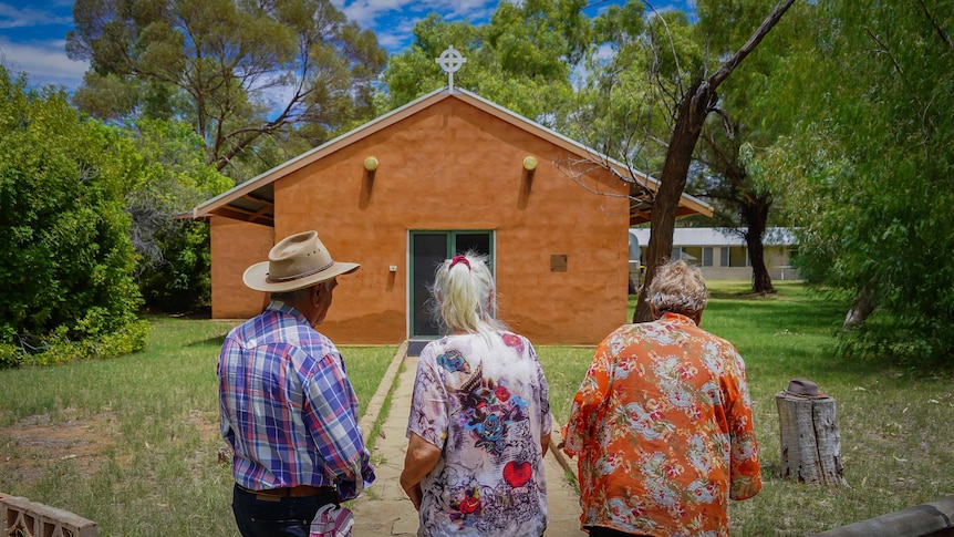 Three people out the front of a church