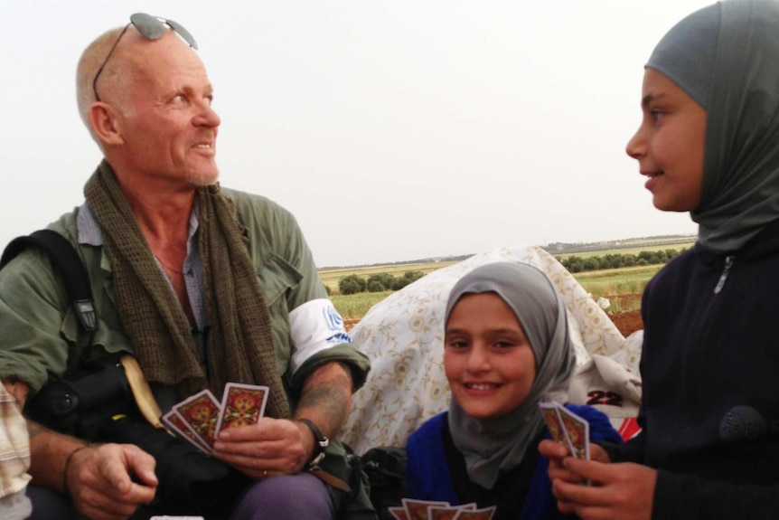 Sebastian Rich plays cards with three Syrian refugees on the Syrian-Jordan border