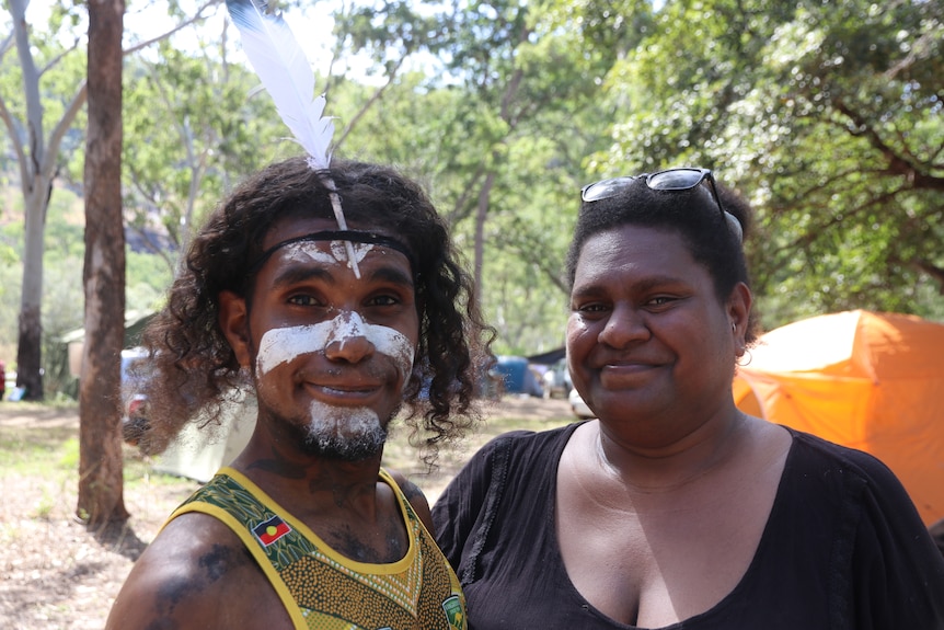 Close up portrait of a man who has a white feather and white face paint, and a woman wearing a black shirt.