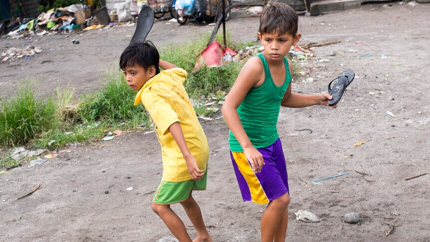 Two children play  game with their thongs in the slums of Angeles City, Philippines, September 2016.