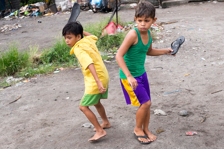 Two children play  game with their thongs in the slums of Angeles City, Philippines, September 2016.