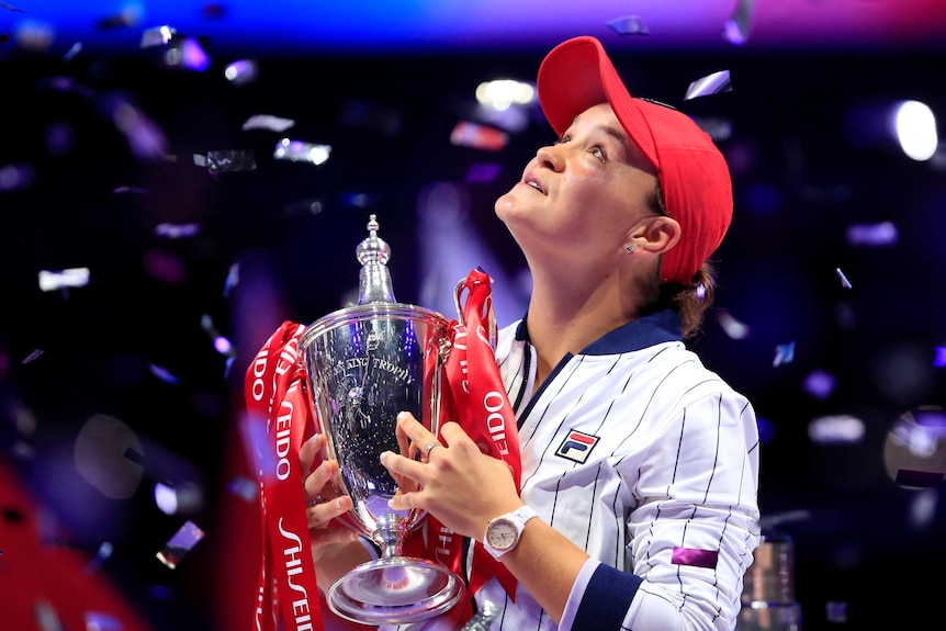 Ash Barty looks up at falling confetti as she holds the WTA Finals trophy after winning the decider against Elina Svitolina.