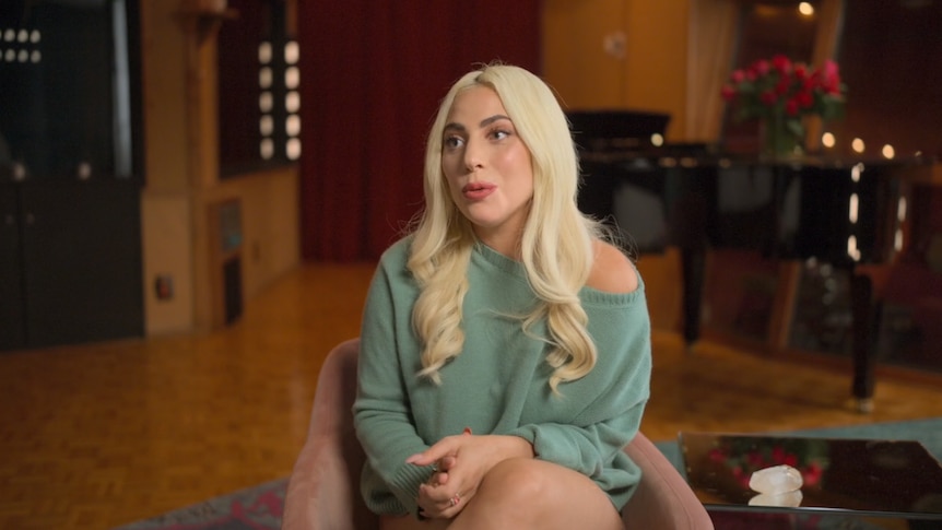 Musician Lady Gaga speaks in an emotional interview, wearing a green sweater