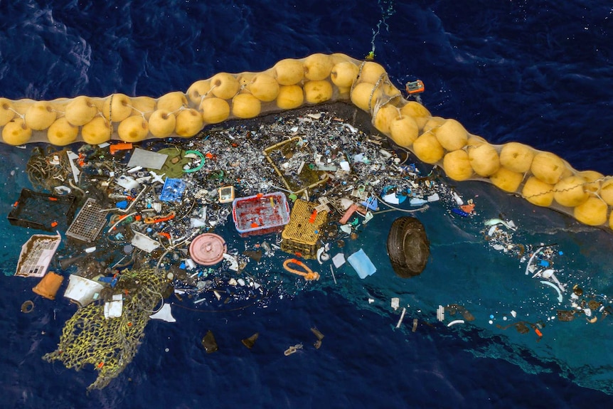 Floating plastic is collected on the ocean's surface by a row of floating corks