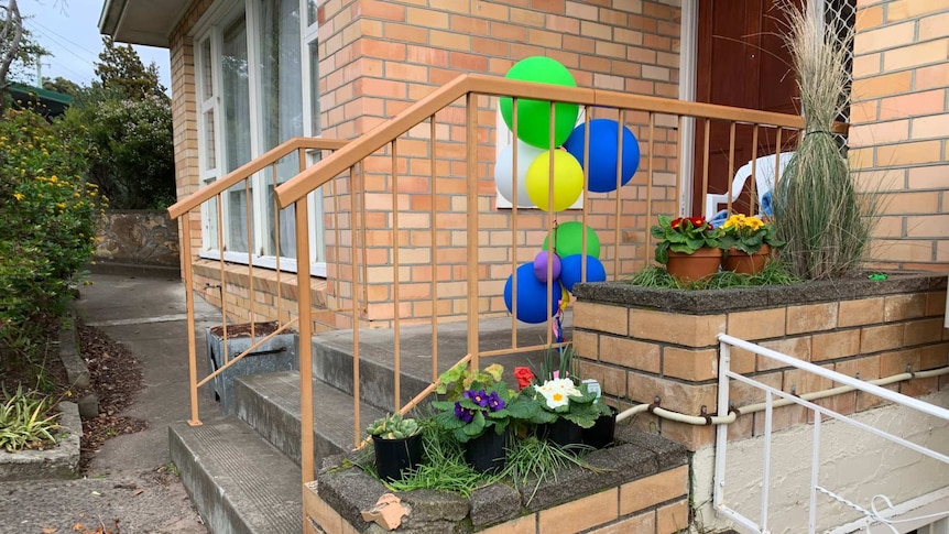 Balloons tied to a banister outside a brick house which was the site of a carbon monoxide incident in South Hobart.