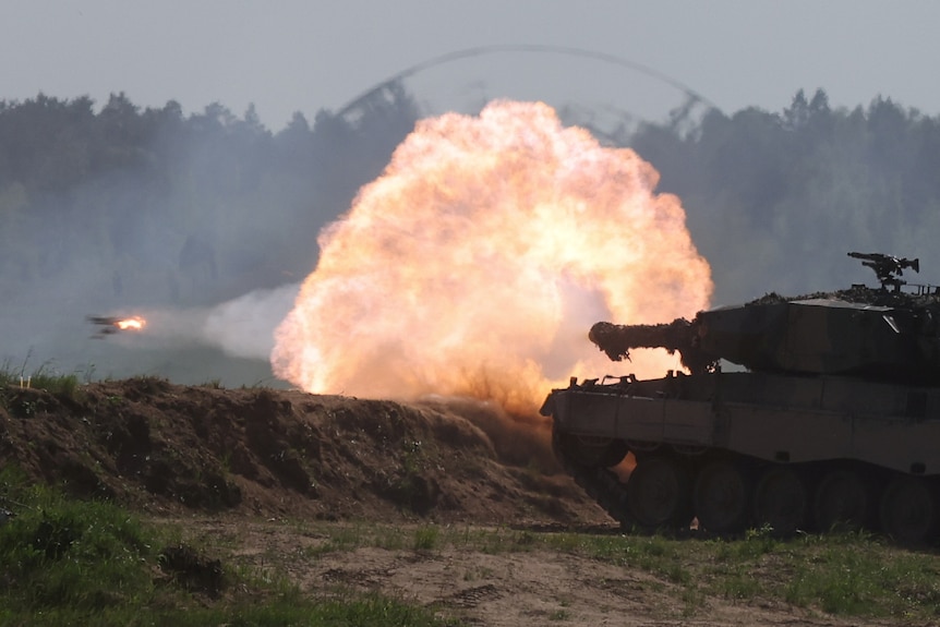 A large blast comes from the barrel of a tank gun during a military exercise.