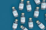 Vaccine vials labelled Omicron coronavirus vaccine on a dark teal background