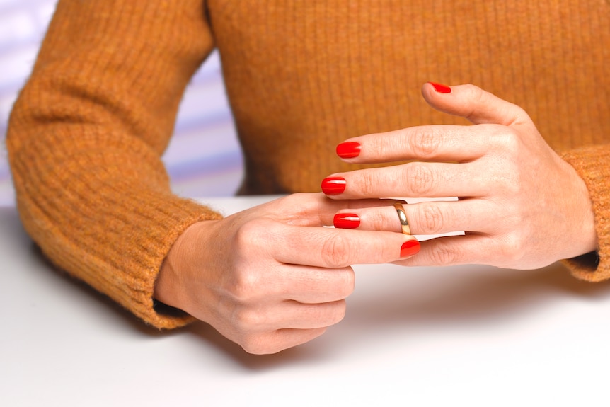 Women taking her wedding ring off her finger.