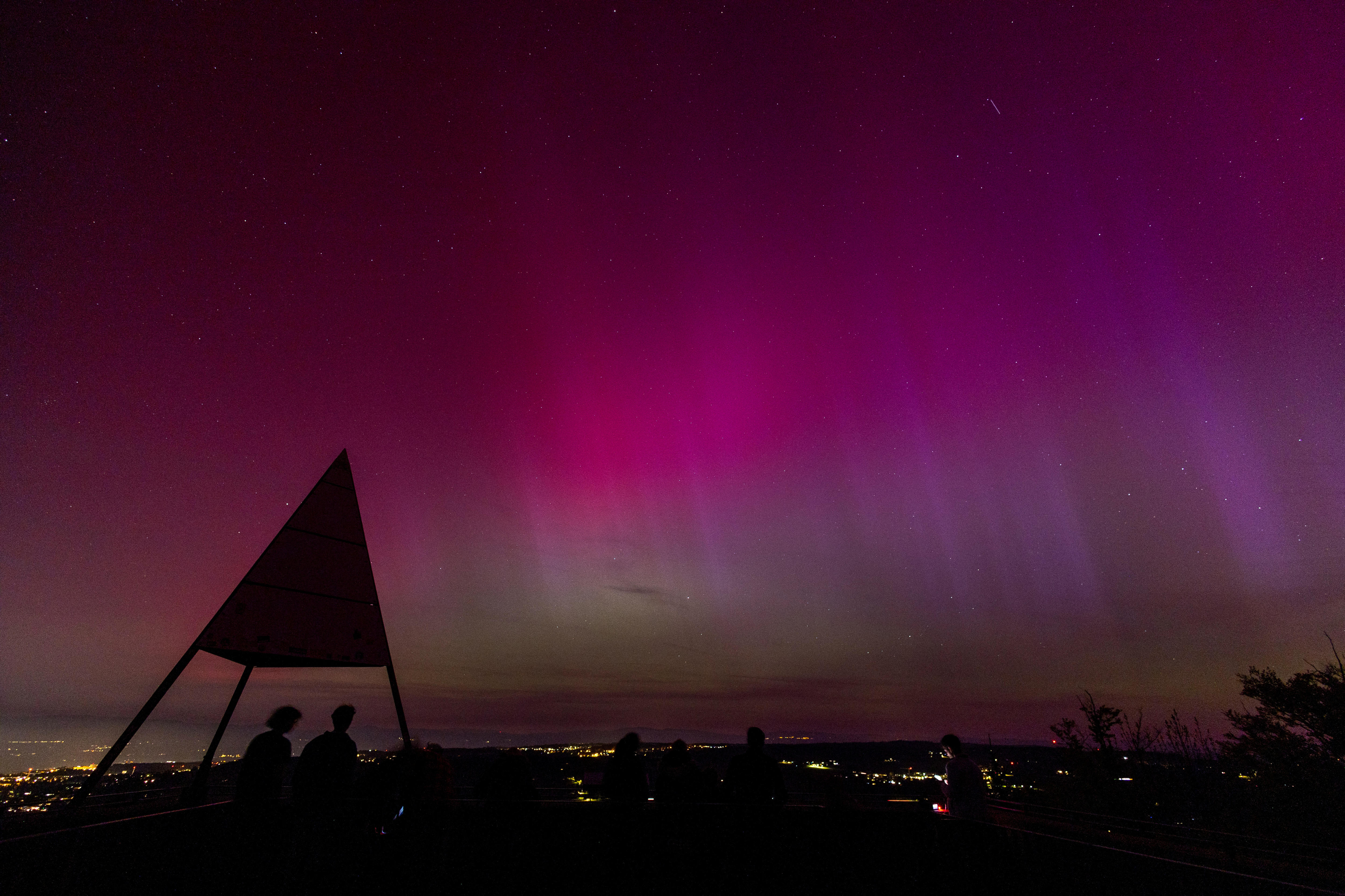 A purple sky filled with vertical streaks over a city.