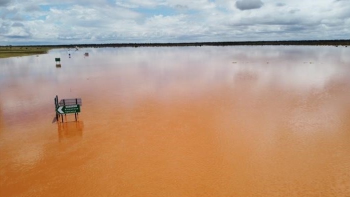 An aerial photo of road signs sticking out of floodwater.